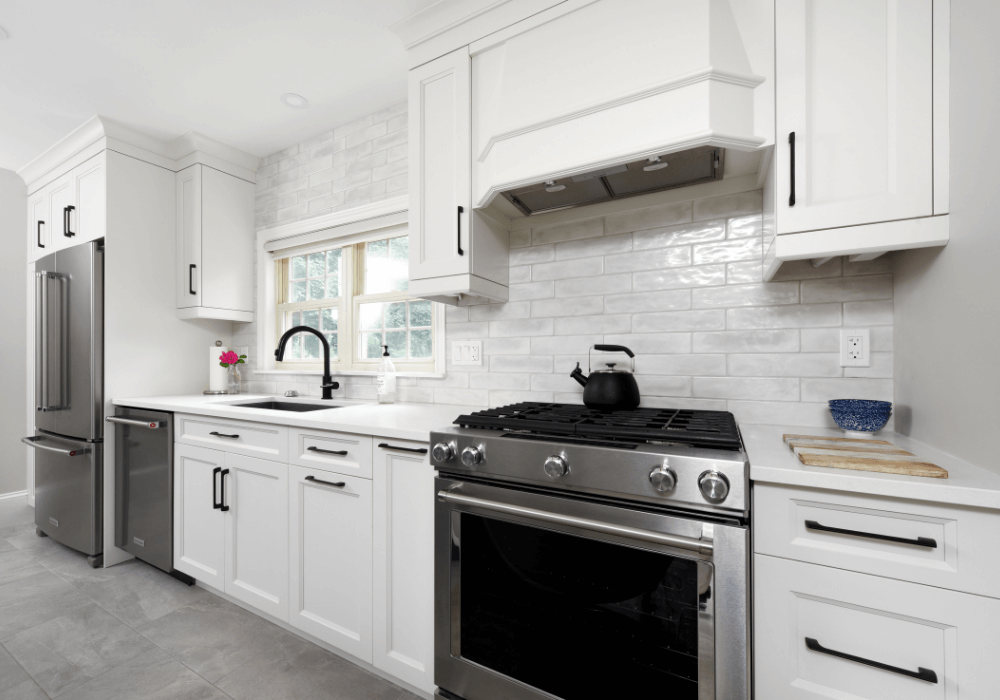 white kitchen showing matte black handles and tap with stainless steel appliances
