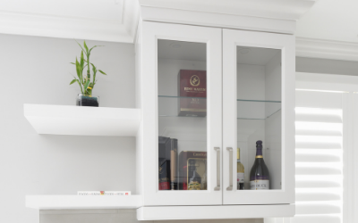 open white shelving with a plant attached to a cabinet with glass from to see in at whine bottles.