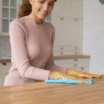 Professional cleaning lady in rubber gloves remove dirt from work top using soft duster