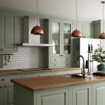 Green kitchen interior with island. Stylish kitchen with wooden worktops. Cozy olive kitchen with utensils and appliances. Close-up of a dining table in the background of the kitchen.