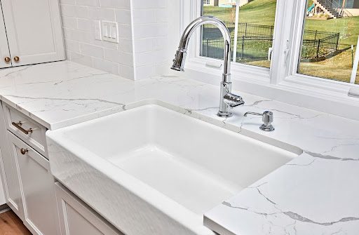 Farmers kitchen sink with white quartz countertop.